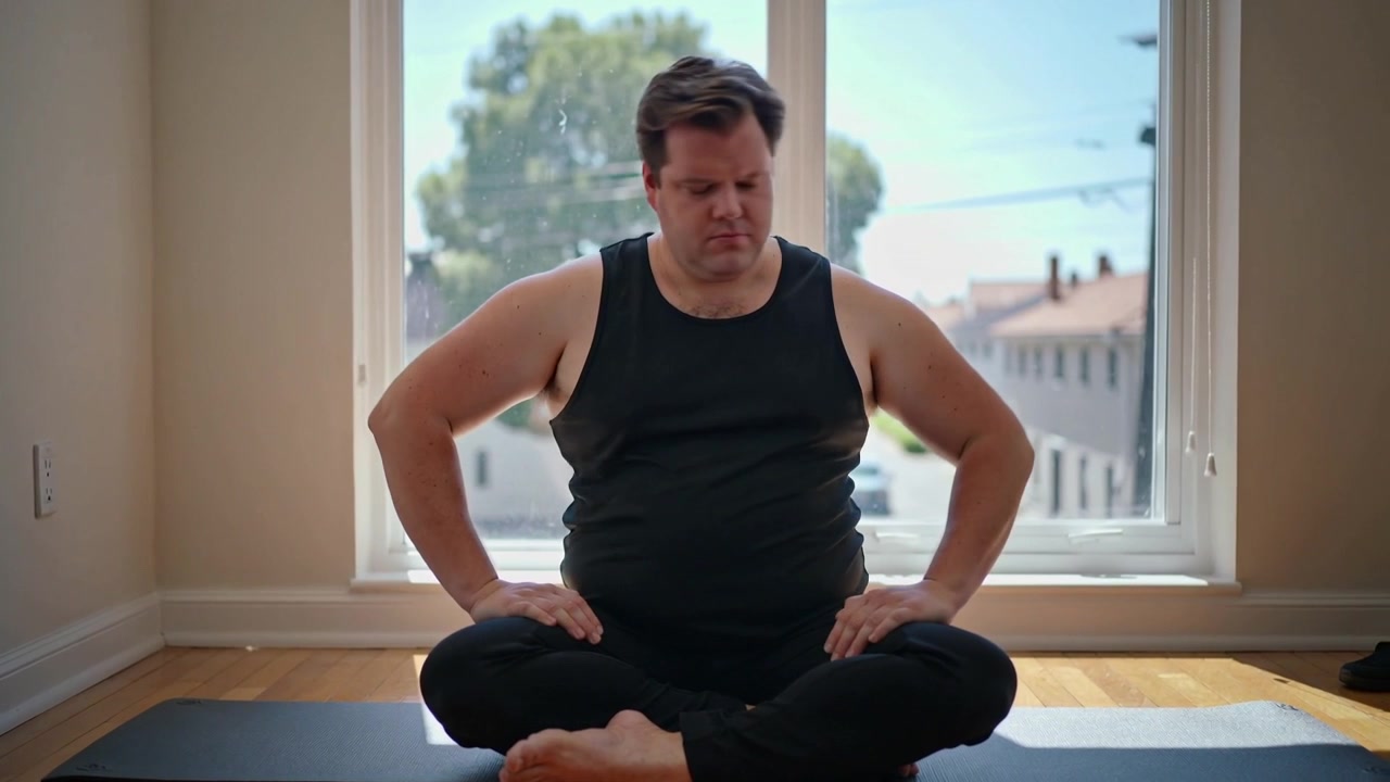 Girando a sinistra, uomo in abbigliamento da allenamento che fa torsioni del busto alla finestra dell'appartamento su un tappetino da yoga, preparandosi