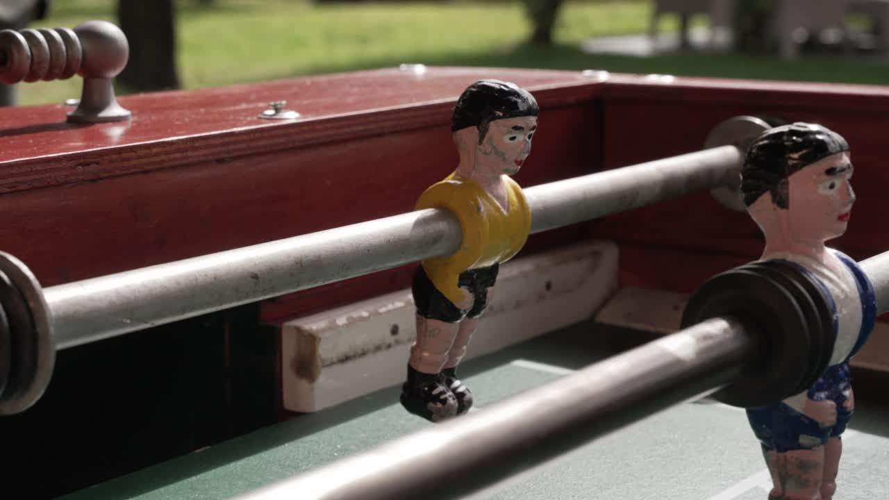 foosball table with worn painted players in sunlight during outdoor leisure play