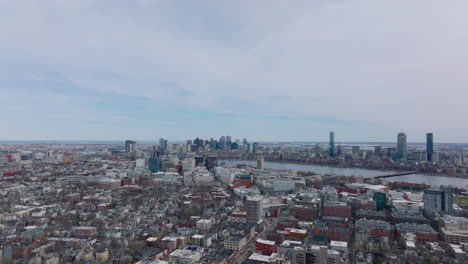 Aerial-ascending-shot-of-large-city.-Cityscape-with-high-rise-business-buildings-in-background.-Town-divided-by-river.-Boston,-USA