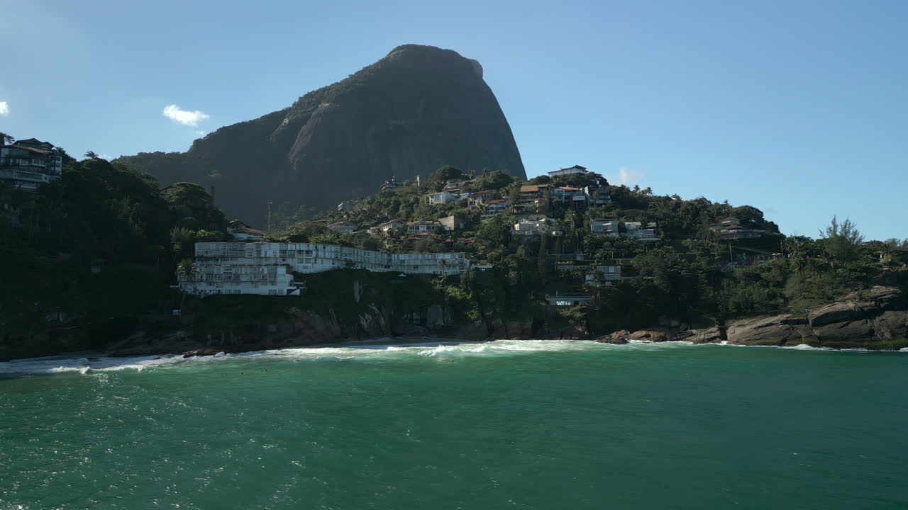 Oceano e case di lusso a Joatinga Beach, Rio de Janeiro. Vista di ville sul litorale roccioso e grandi colline in 4K Apple ProRes 422. Ripresa aerea con tracking a sinistra sopra l'acqua durante la mattina