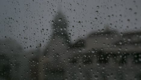 during a dark, gloomy and overcast weather, a close-up view of a rainy glass as rain drops are seen on a window