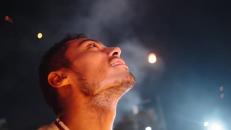 man looking up at fireworks at night
