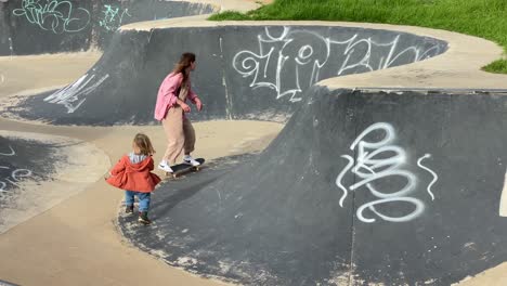 wide view of happy girl skateboarding and her brother running behind her in summer in estoril, cascais