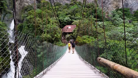 suspension bridge over a waterfall crossed by visitors, an adventurous experience in lush surroundings