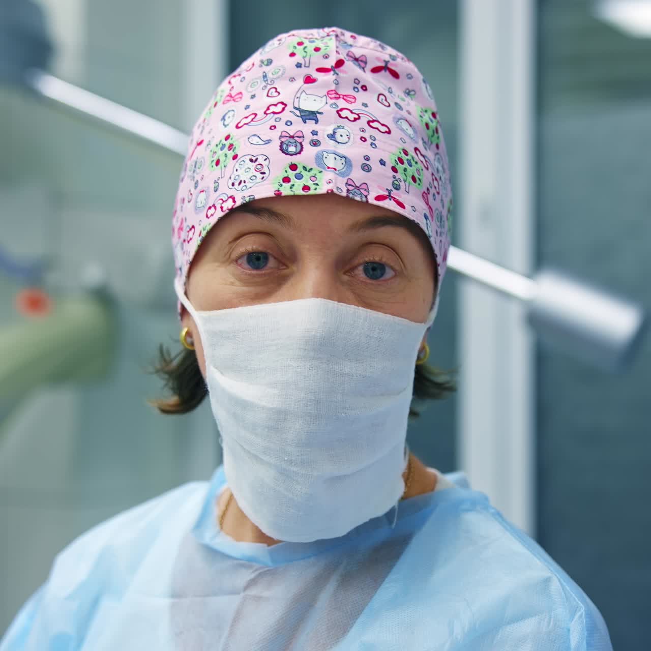 Doctor in scrubs and facial mask tells methods of vision correction to the camera. Modern clinic background