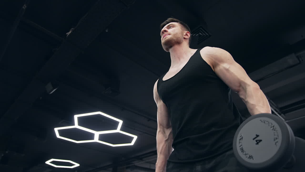 Fitness man with dumbbells in gym. Young man doing workout in luxury fitness club