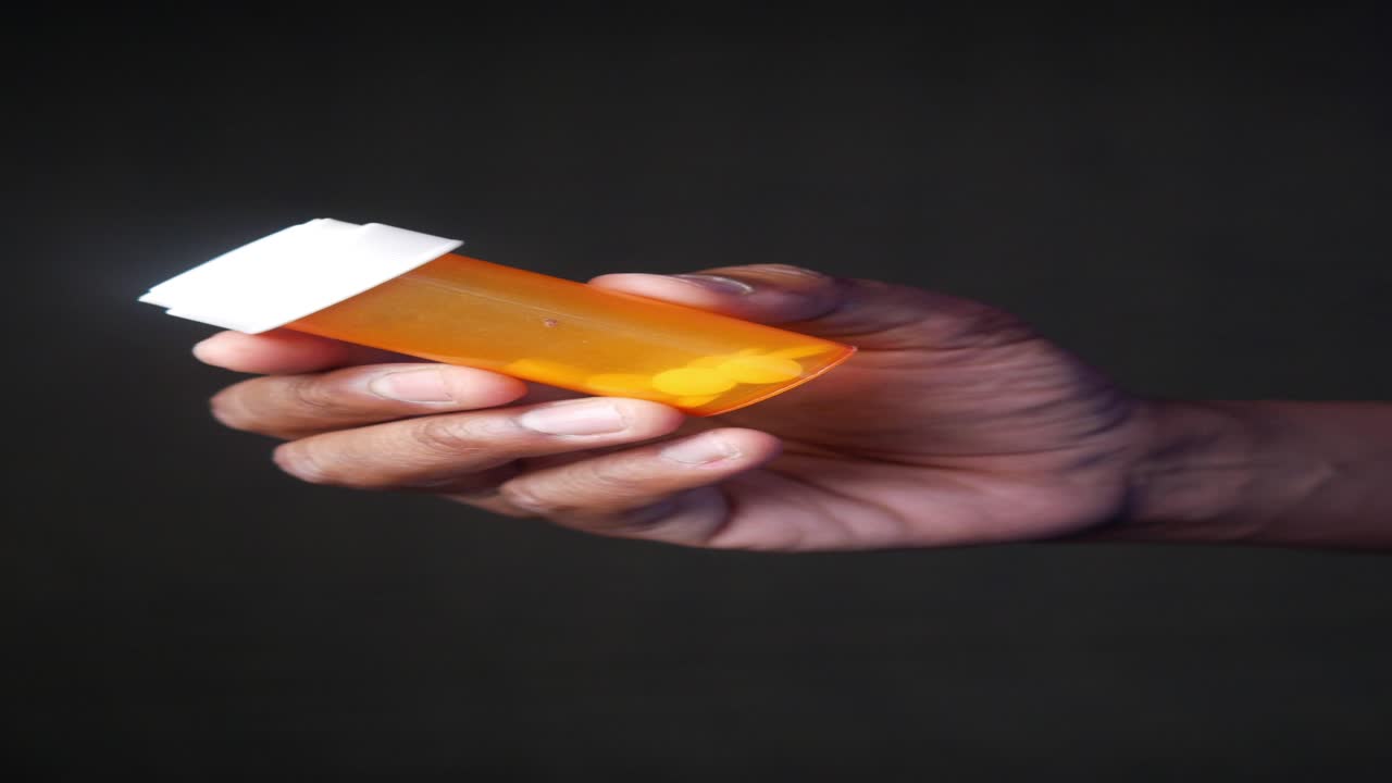 una mano sosteniendo un frasco de pastillas