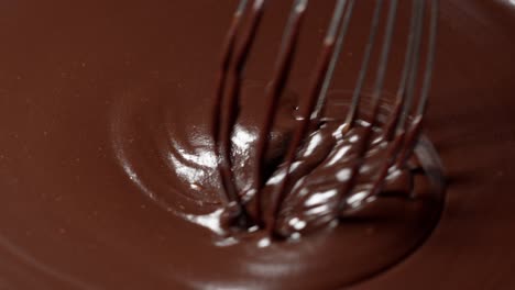 Slow-motion-mixing,-stirring-premium-dark-melted-chocolate-with-a-whisk,-process-of-making-sweets