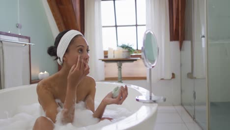 Mixed-race-woman-taking-a-bath-applying-beauty-face-mask