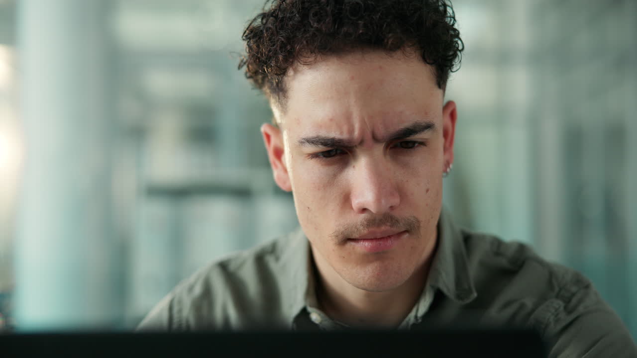 Young Man with Curly Hair Concentrating on Computer Screen in Office