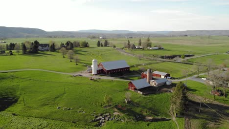 aerial push-in shot on farm toward multiple barns during summer in west virginia