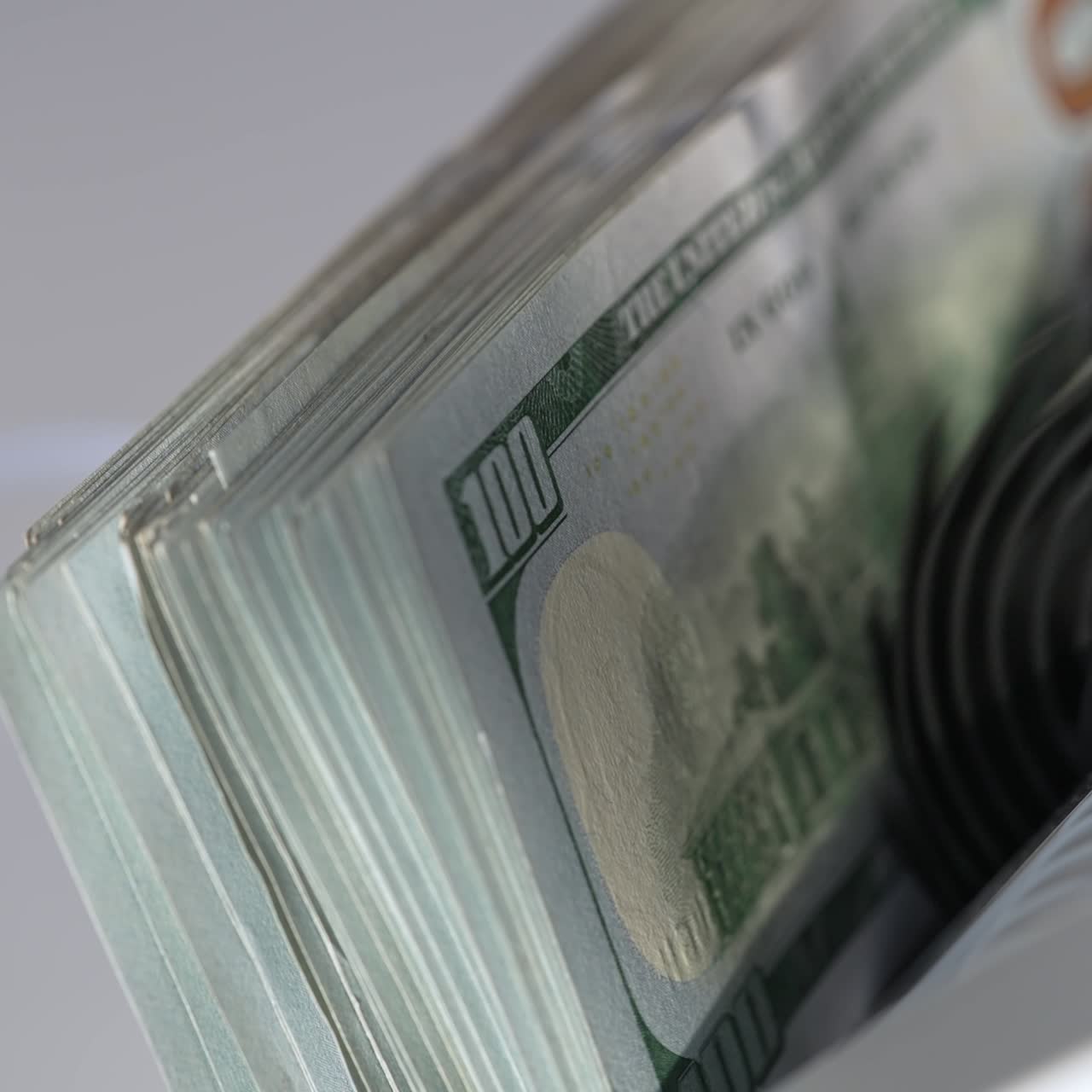 American dollar bills of hundred denomination rotated in cash machine. Apparatus counts and then stops. Close up