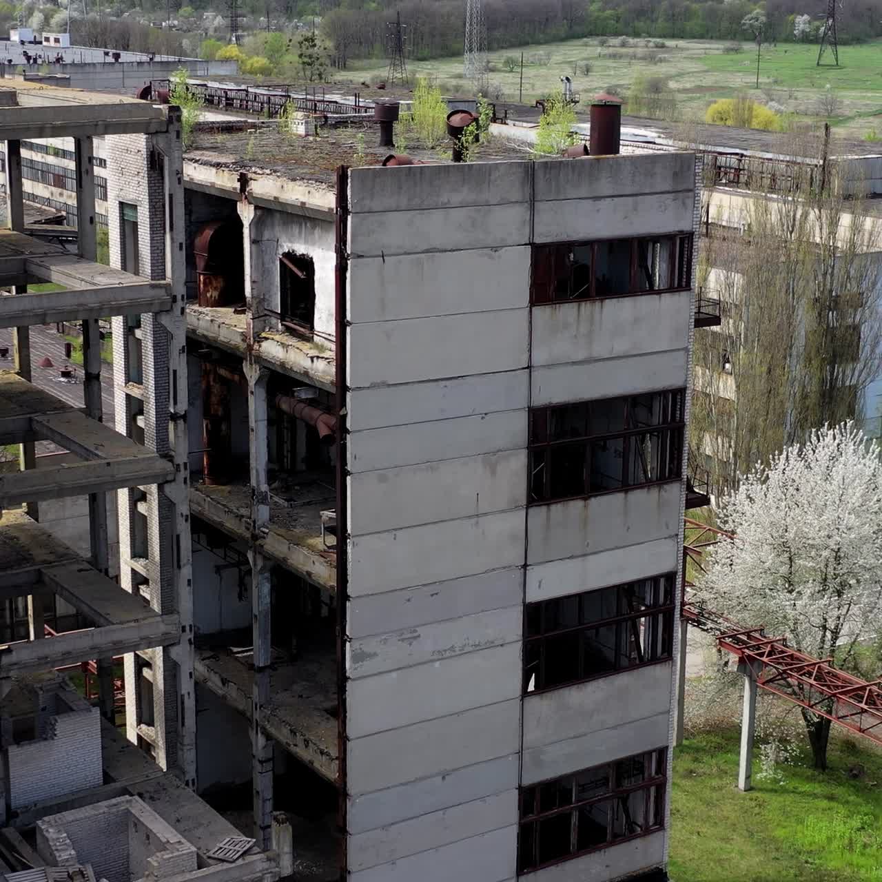 Damaged industry. Abandoned place with old unfinished buildings of a factory. Old industrial plant in springtime. Drone view