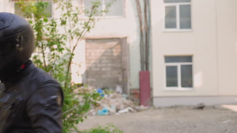 motorcyclist closes helmet visor against abandoned building