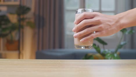 man hand place glass of chocolate milk on table