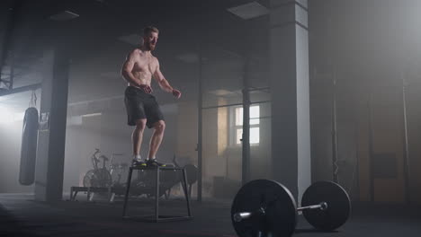 Slow-motion:-Muscular-Shirtless-Fit-Man-Energetically-Box-Jumps-in-Hardcore-Gym-doing-Part-of-His-Cross-Fitness-Training-Plan.-Man-is-Sweaty-from-Intense-Workout