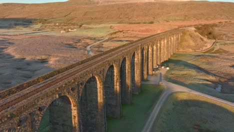 arched viaduct railway bridge crossing barren yorkshire moorland at dawn in winter