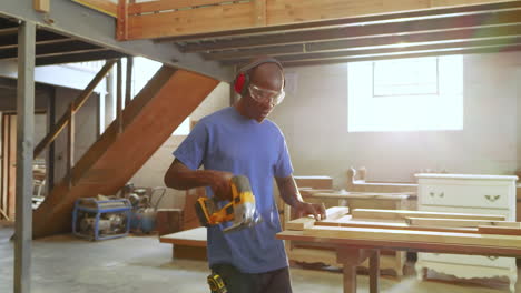 entering woodshop, african american man marking plank, cutting with jigsaw and measuring cut