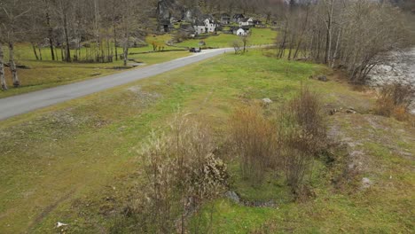 a road curls along the river and approaches rural tiny houses scattered on the hill of cavergno village in vallemaggia, switzerland