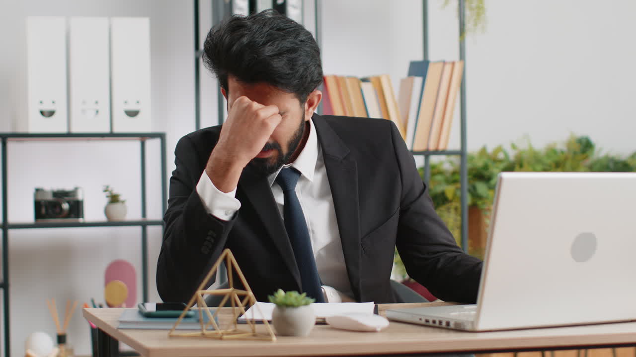 Tired indian business man suffering from headache problem tension migraine stress at home office