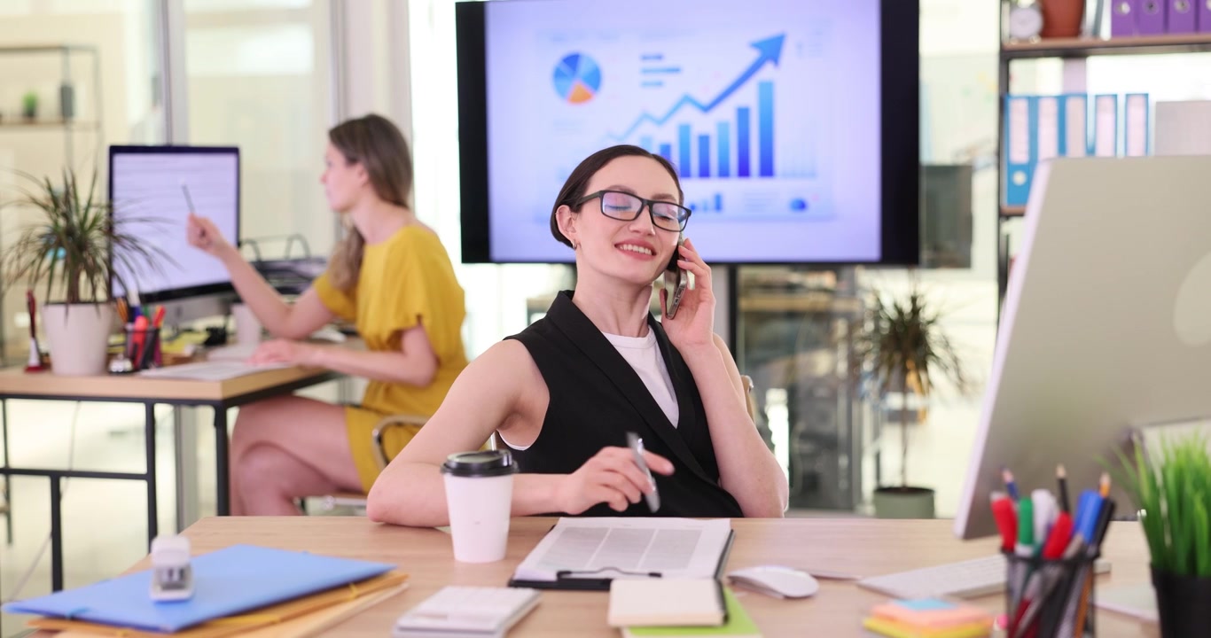 Cheerful secretary in elegant attire happily talks on phone