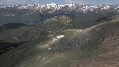 Aerial:-Cloud-shadow-moves-over-grassy-summit-meadow-in-CO-mountains