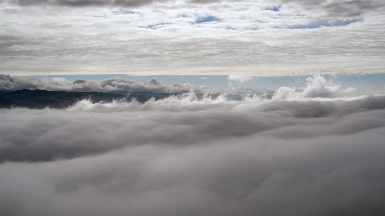 Aerial View of Thick Clouds Moving Over Mountain Landscape