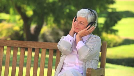 elderly woman listening to music on a bench