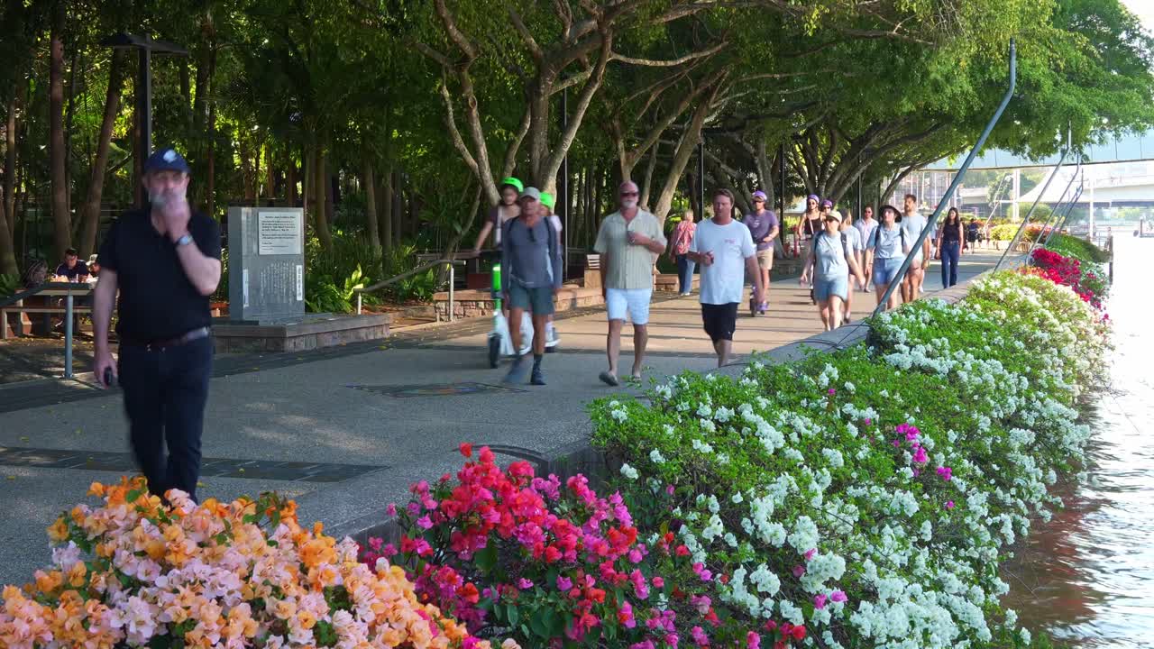 People walking and strolling along the riverside Clem Jones Promenade in South bank on the weekend, a tranquil oasis of Brisbane lifestyle recreational precinct by the river.