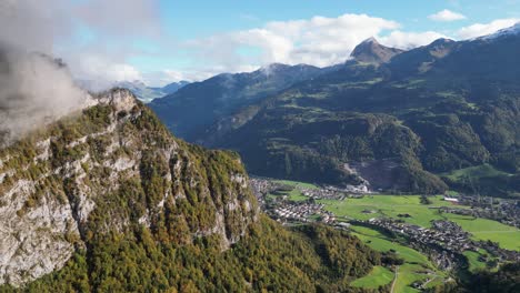 zoom out toma aérea de las montañas con árboles densos altas cumbres que alcanzan las nubes