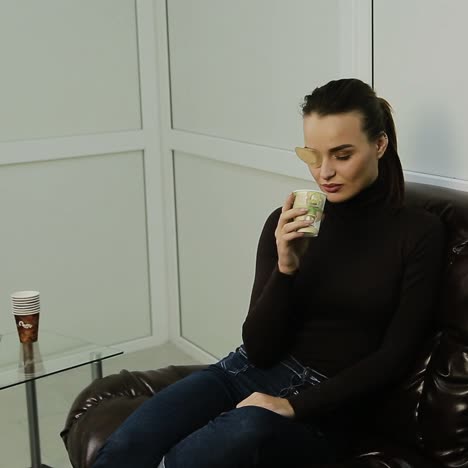 woman with an eye patch, sitting and drinking coffee