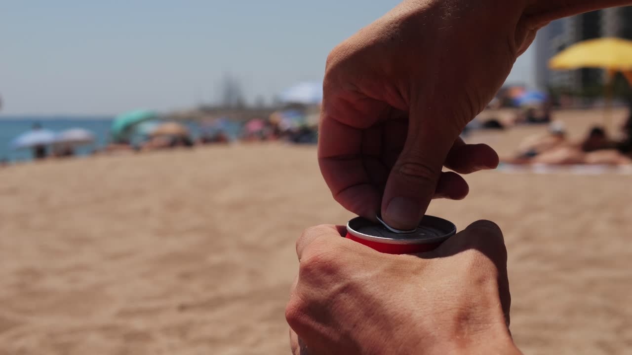 Opening a can of soda on a beach