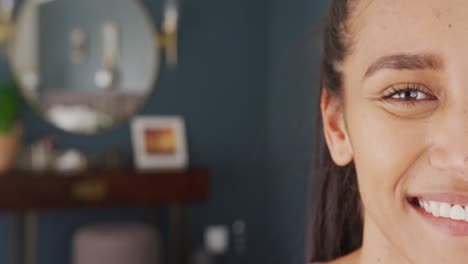 retrato de mitad de cara de una mujer biracial feliz en casa, sonriendo a la cámara, con espacio para copiar.