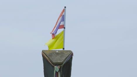 a flag whipping around in the wind sitting on the top of a boat