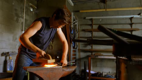 female metalsmith  brushing horseshoe in fire 4k