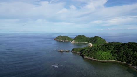 Aerial-View-of-island-with-lush-jungle-facing-turquoise-ocean