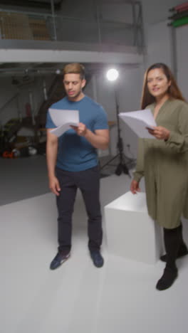 vertical video shot of actors rehearsing scene and waving at camera in studio with film sound recordist