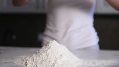 Female-hands-break-the-egg-into-flour-on-the-kitchen-table.-Slow-Motion-shot