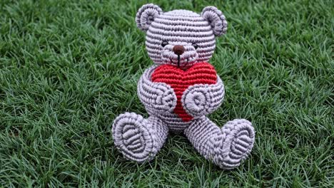 crochet teddy bear with red heart on grass