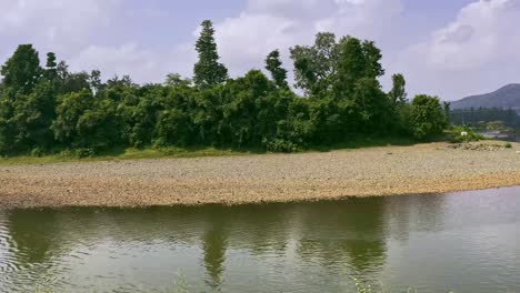 Beautiful-Scenic-panning-shot-of-Saputara-hill,-clear-river-passing-through-the-green-forest-in-the-mountains-Gujrat-India-4K