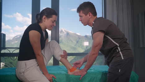 fisioterapeuta aplicando cinta adhesiva en el tobillo del paciente