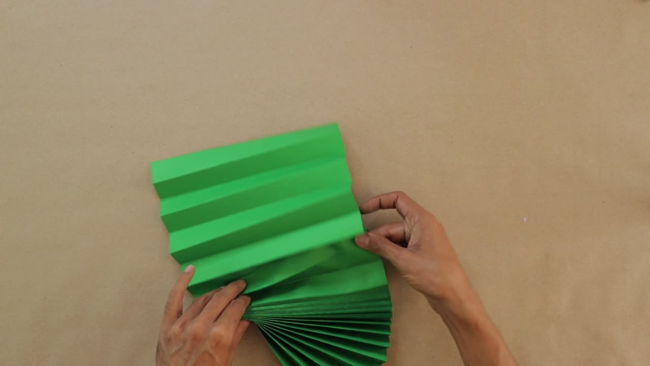 pedazo de papel, de color verde, doblado elegantemente en la forma de un abanico