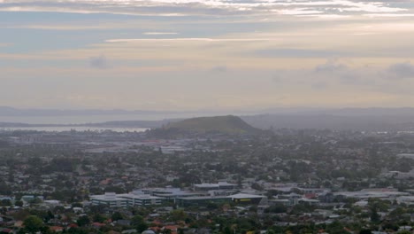 Panoramic-view-of-Auckland,-crepuscular-rays-through-misty-clouds-above-New-Zealand