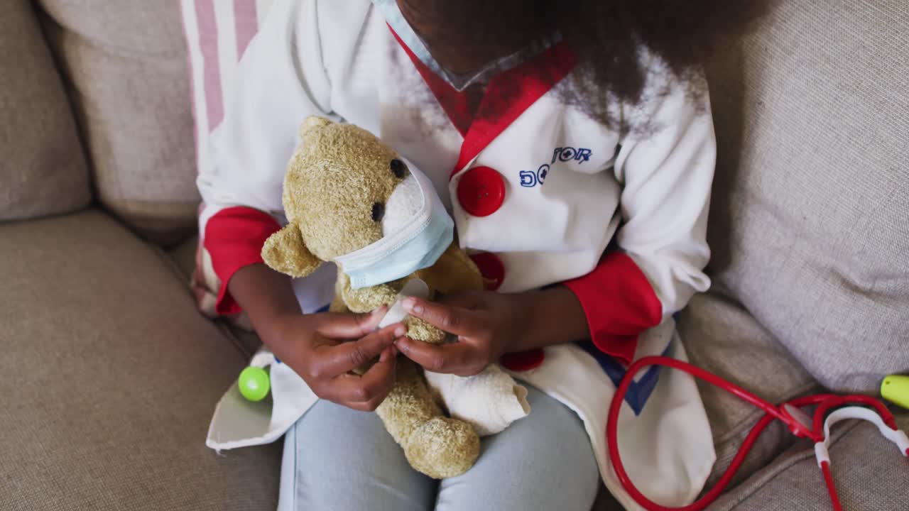African american girl playing doctor and patient with her teddy bear