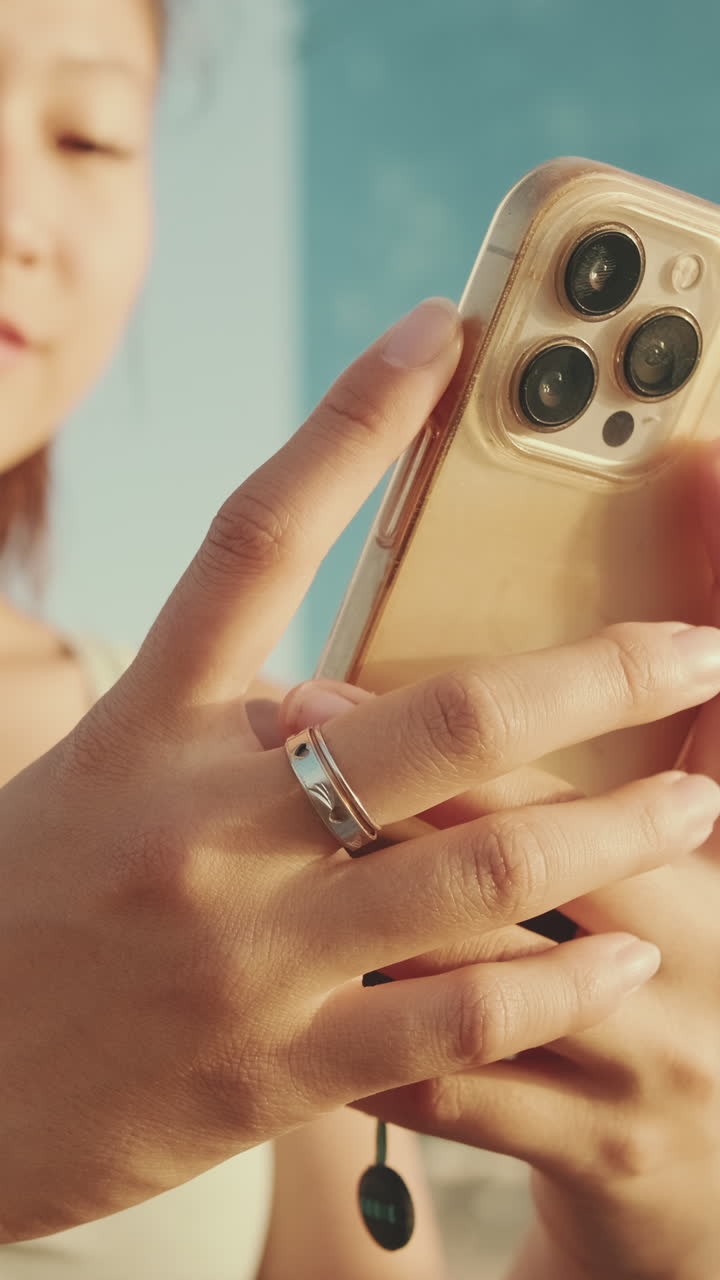Donna che tiene in mano un iPhone con un anello al dito