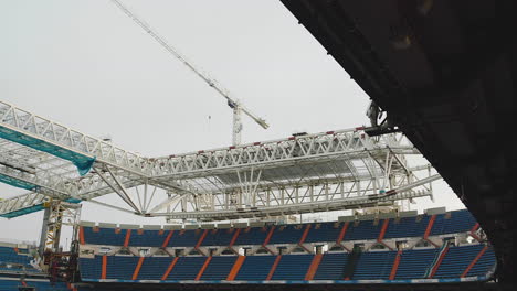 steel roof trusses and tower crane over bleachers at stadium construction site