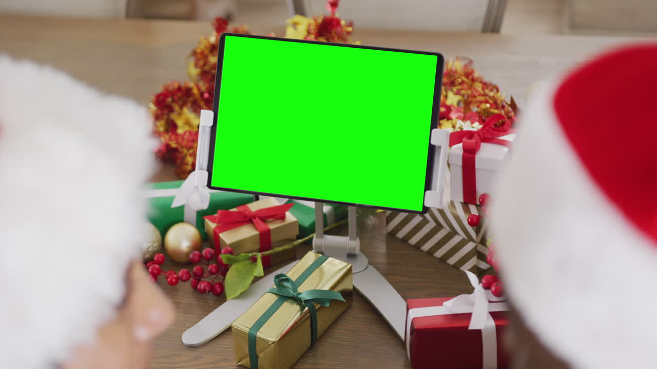 pareja diversa con sombreros de santa teniendo llamada de video de tableta con espacio de copia