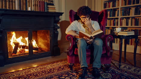 man reading in a cozy library by the fireplace