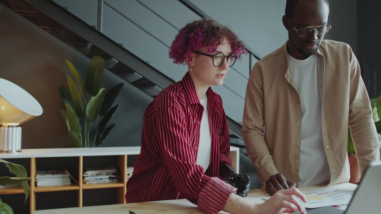 Businesswoman with Prosthetic Arm Discussing Project on Laptop with Colleague
