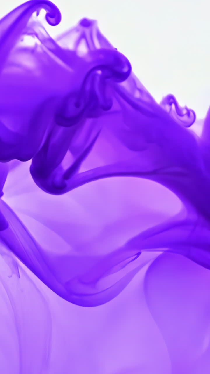 Purple Ink Swirls in Water Creating Abstract Patterns. Vivid purple ink disperses in clear water, forming unique and fluid shapes. Vertical video